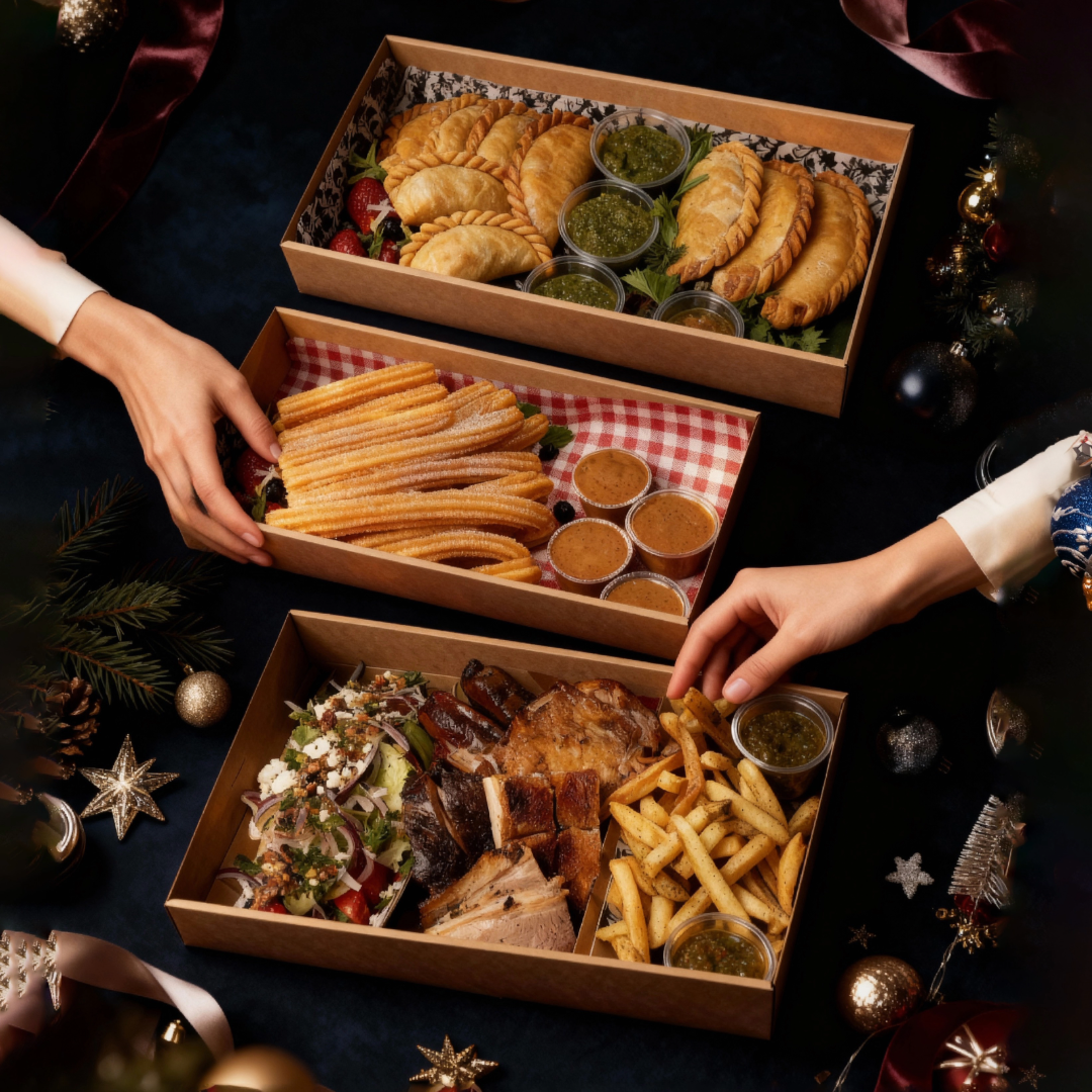 A festive spread from La Boca Sydney’s Christmas Box 2 Go, showcasing empanadas with chimichurri, churros with dipping sauces, and a generous selection of woodfire asado meats, fries and salad.